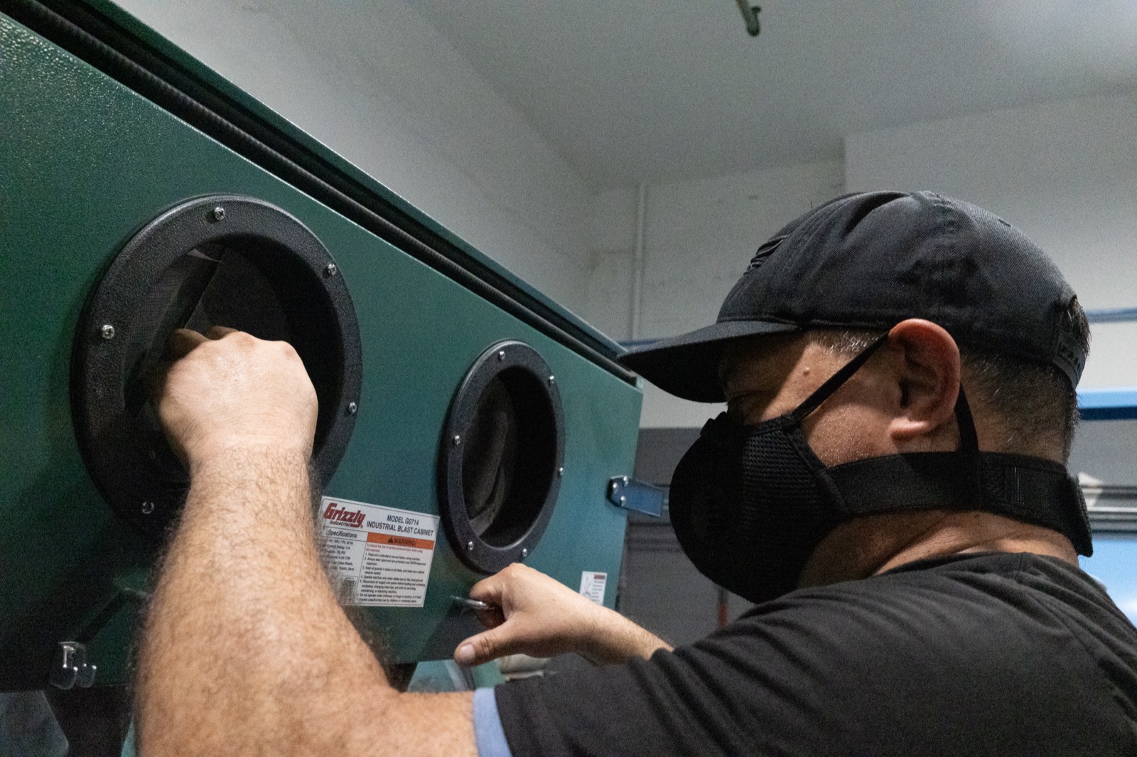 Technician bead blasting a part for a uniform surface finish