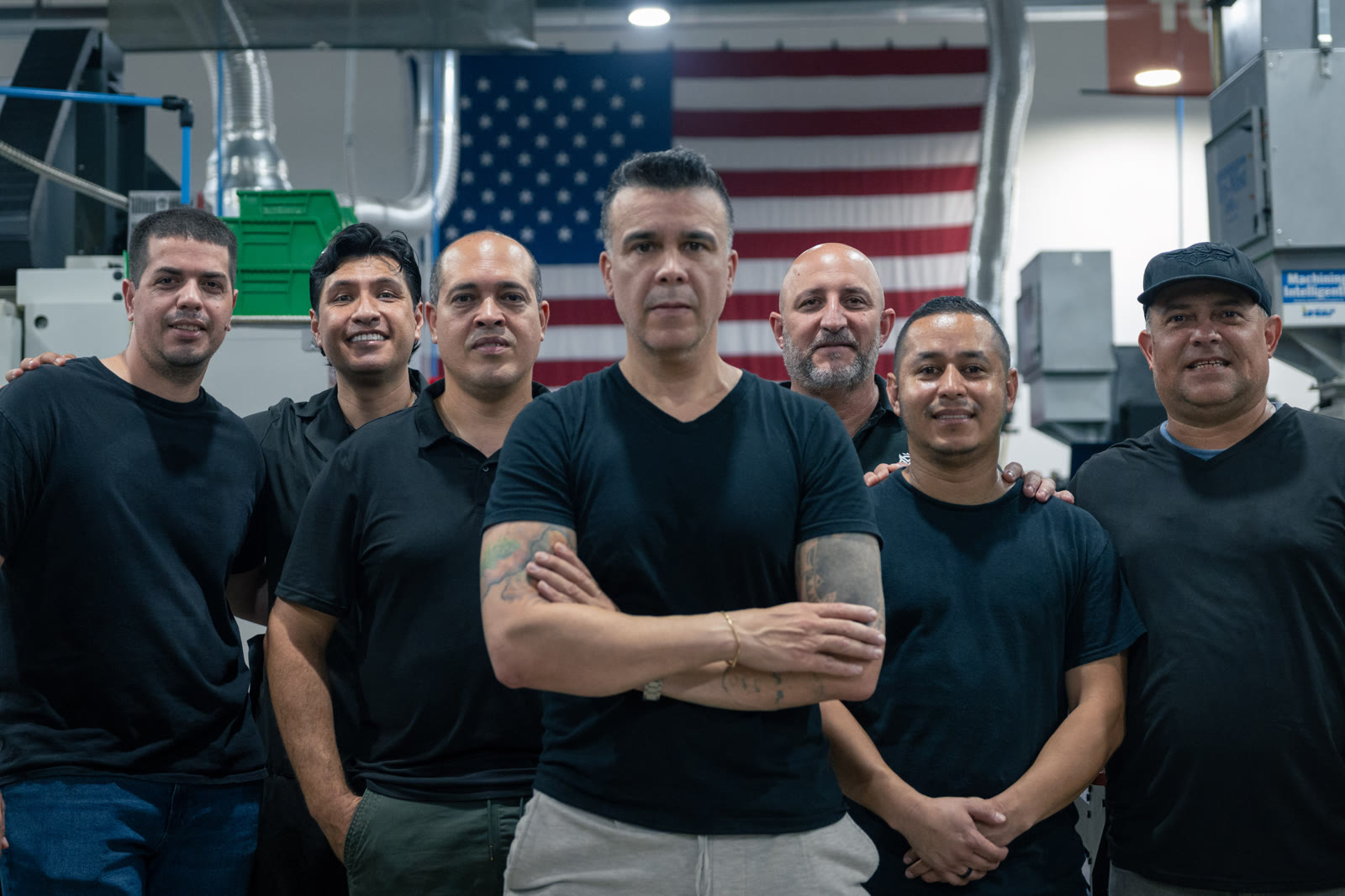 The Manufacture US team in front of the American flag on the shop floor