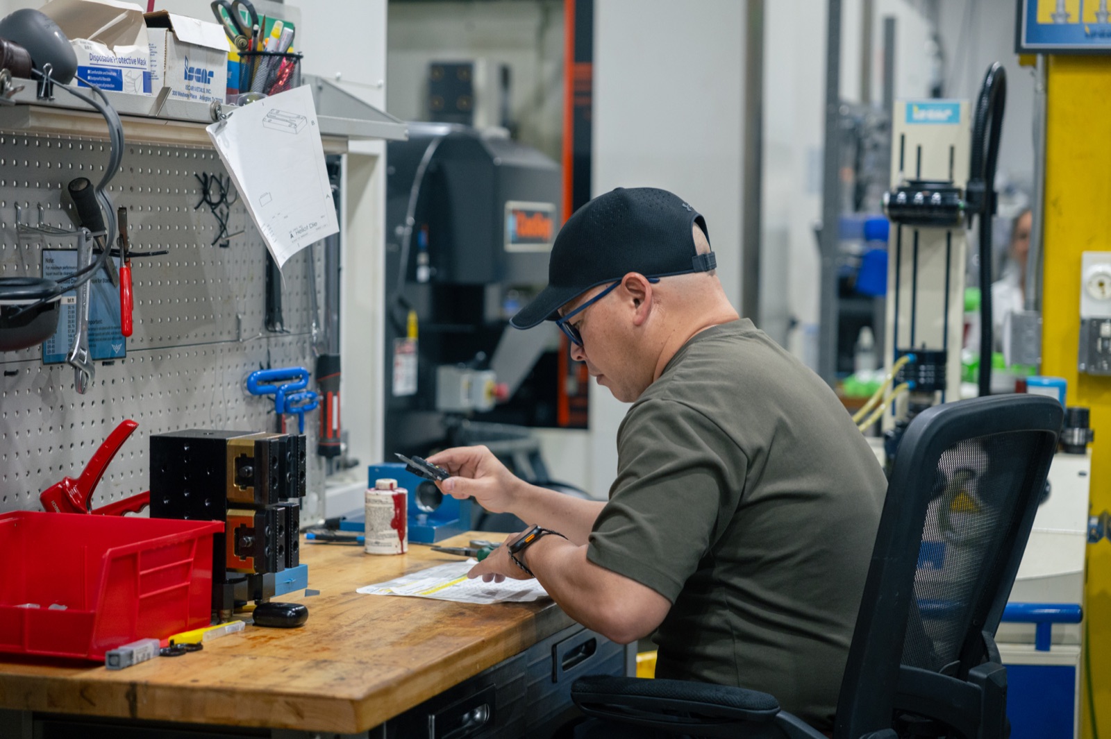 Machinist inspecting a finished machined part at the workbench