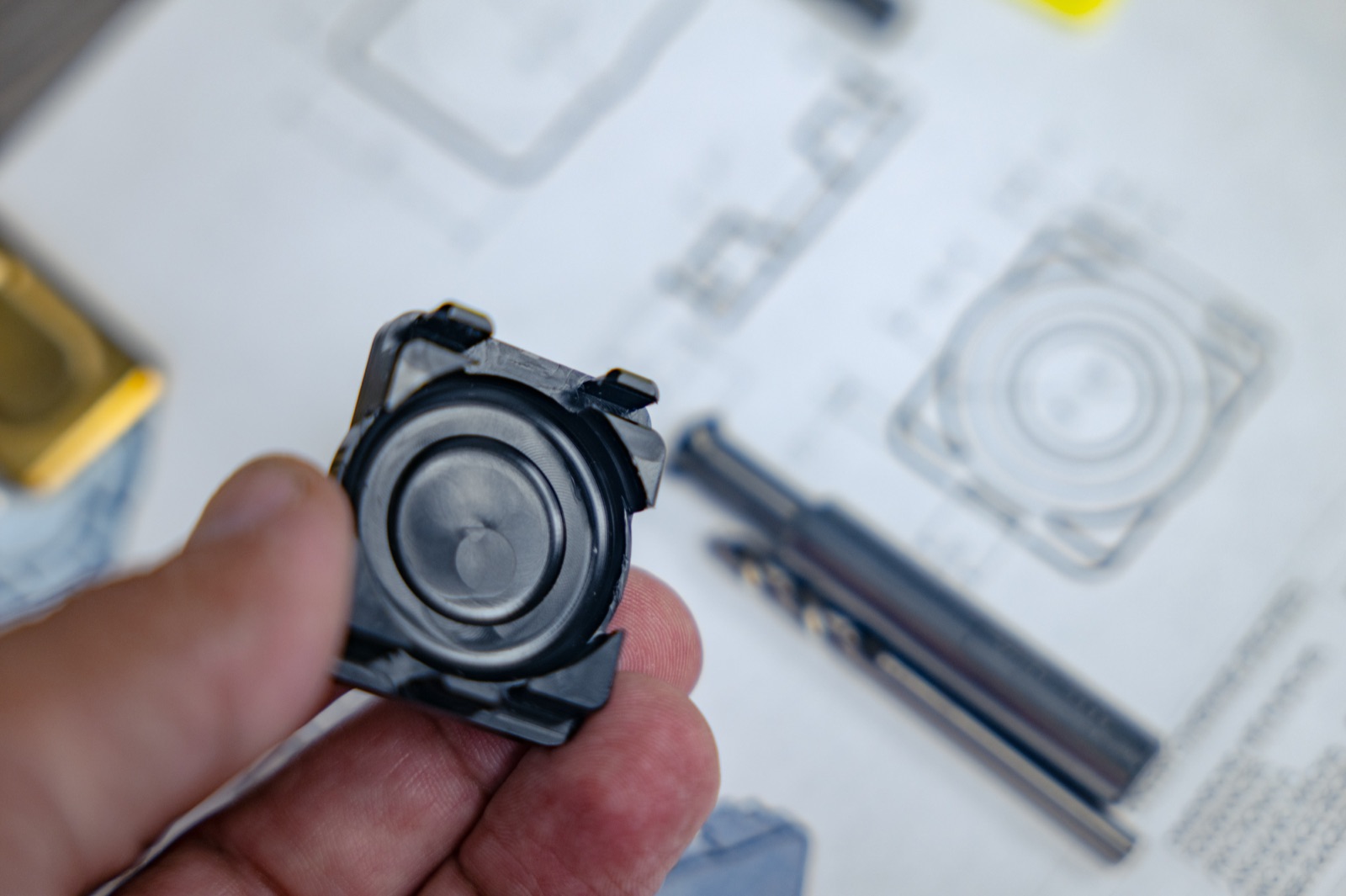 Precision machined cylindrical component beside its engineering drawing