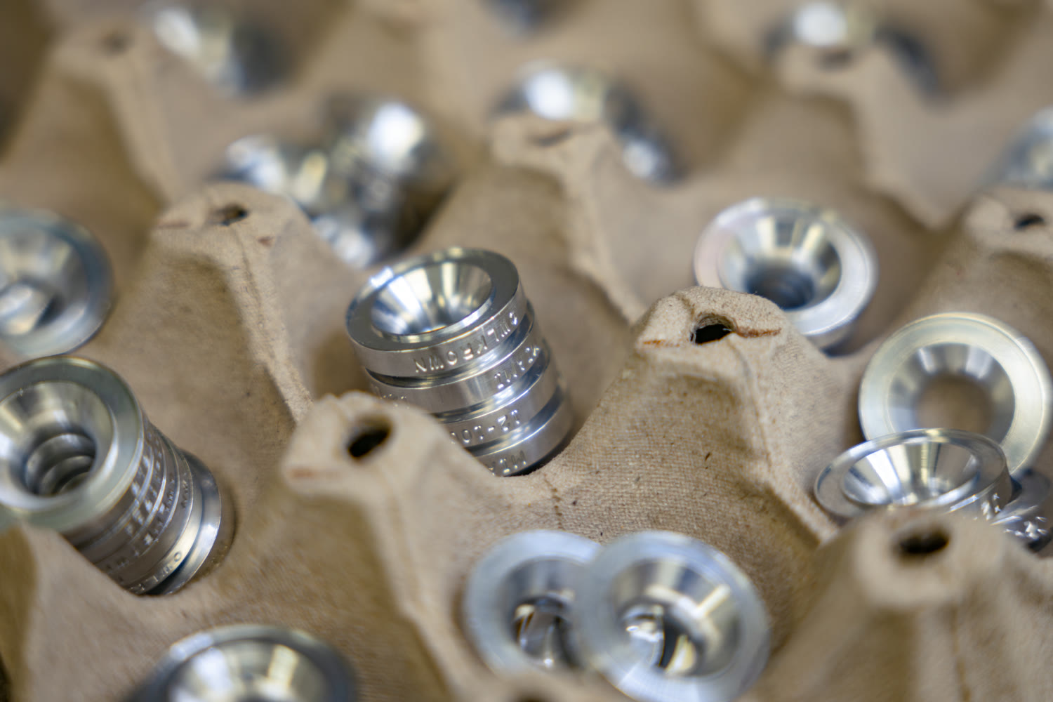 CNC turned aluminum bushings resting in a molded pulp tray after machining